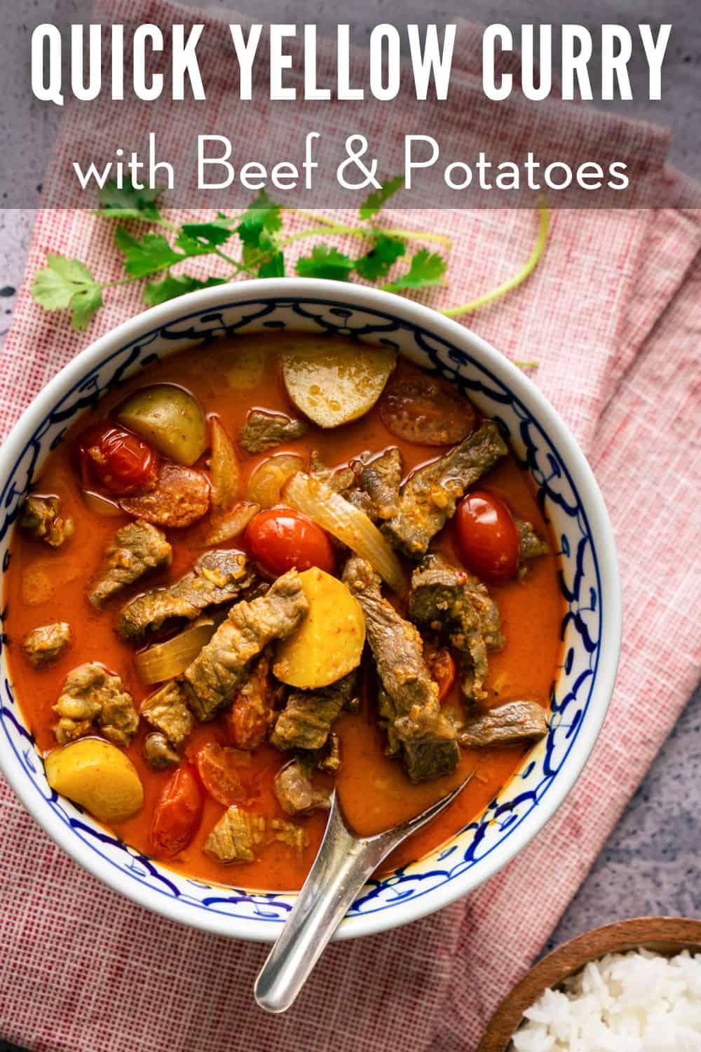 A bowl of yellow curry beef with a cilantro sprig on the side